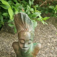 stone bust sculpture depicting an African woman with elaborate headdress